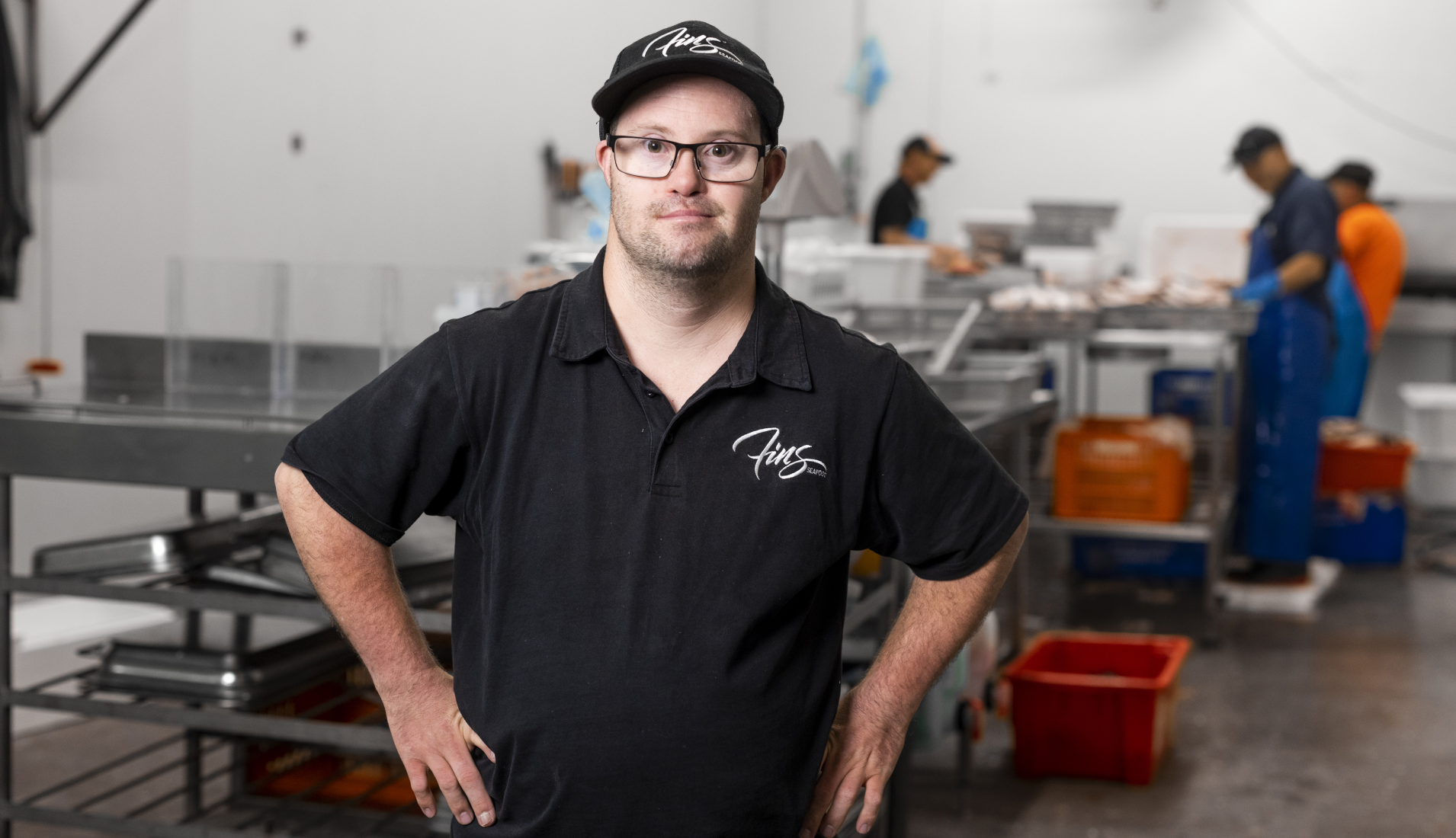 A man with Down syndrome stands smiling in a warehouse where we works
