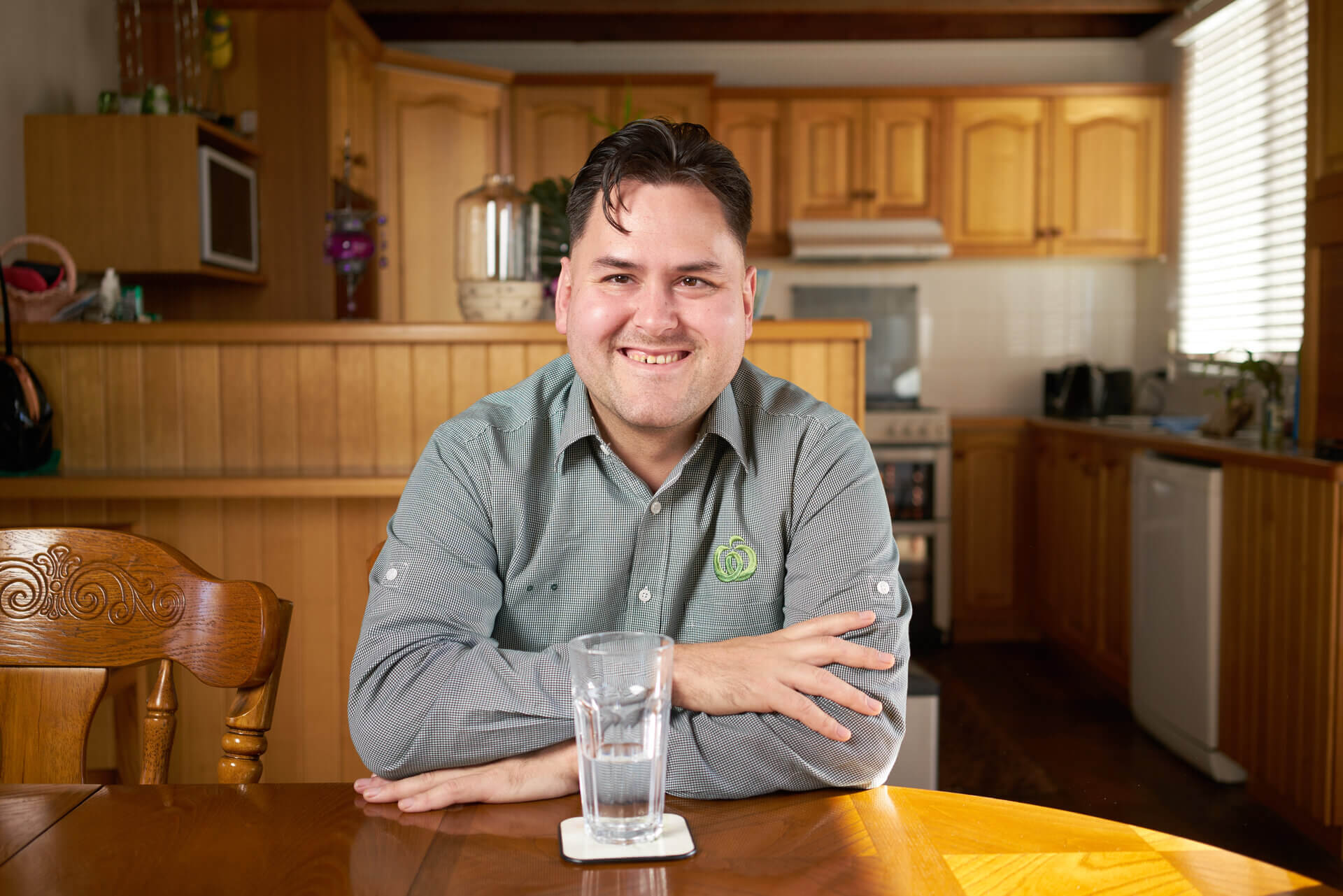 Caley sits at a table smiling in his work uniform